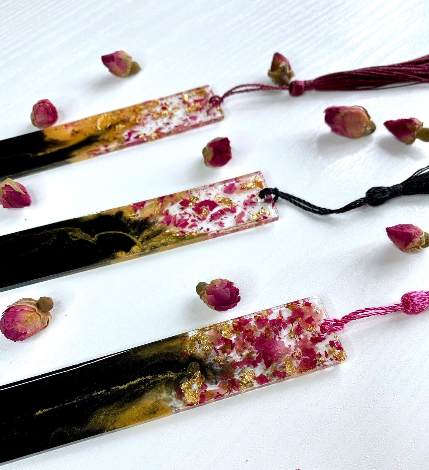 Close-up of black and gold resin bookmark showing dried rose petals and gold leaf in clear resin with matching tassel