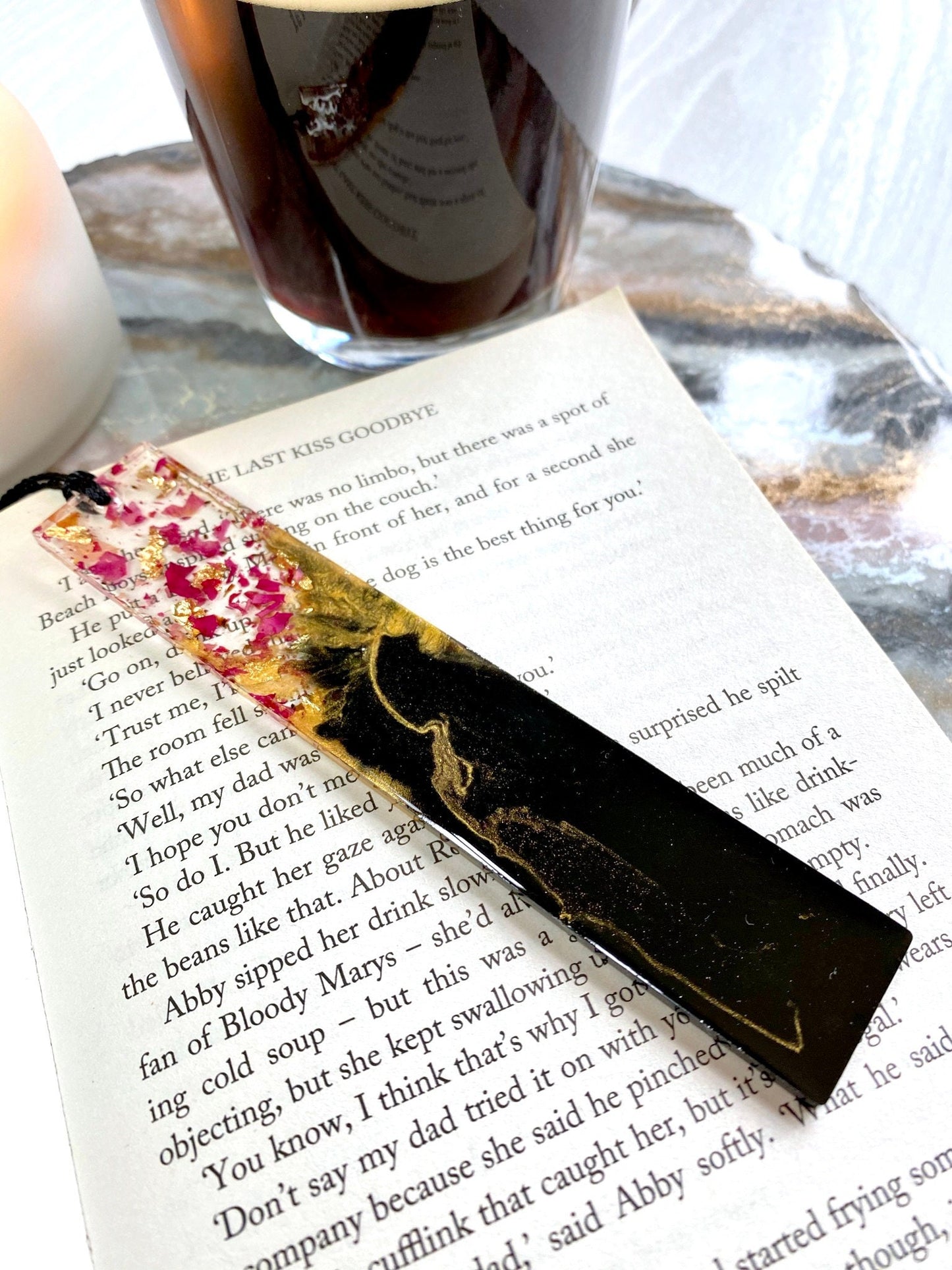 Decorative black and gold bookmark with dried rose flowers design on a book close up