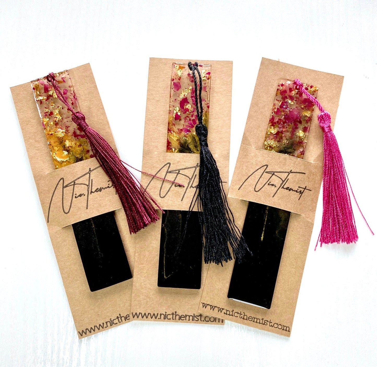 Black and gold resin bookmark with dried rose petals in branded packaging sleeve with Nic.Themist logo