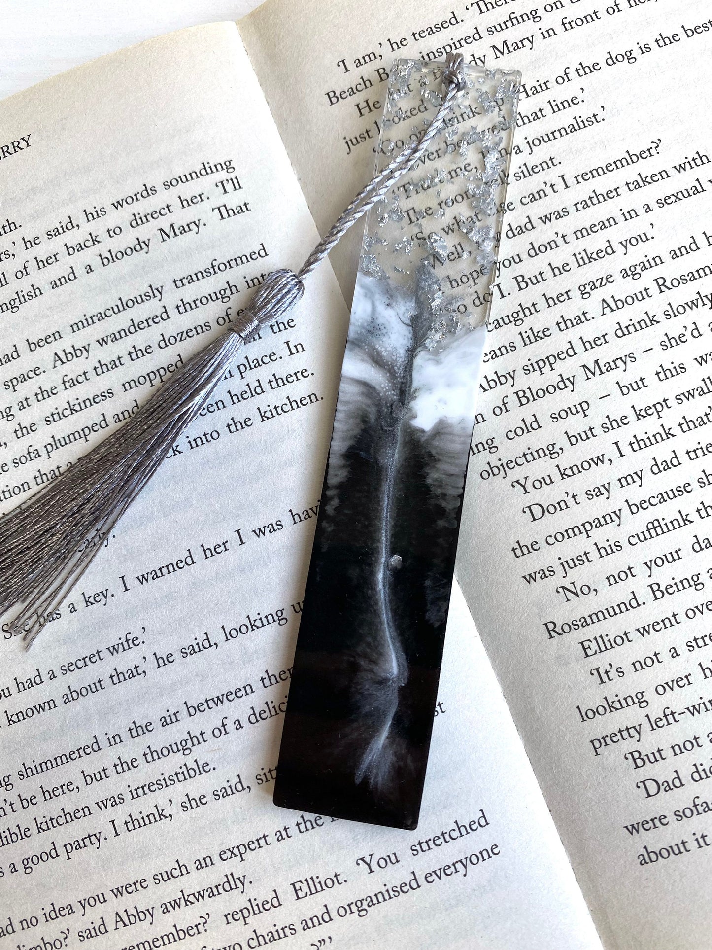 Black & White resin bookmark with silver leaf, non-personalised, placed inside an open book, handmade bookmark for readers or gifts.