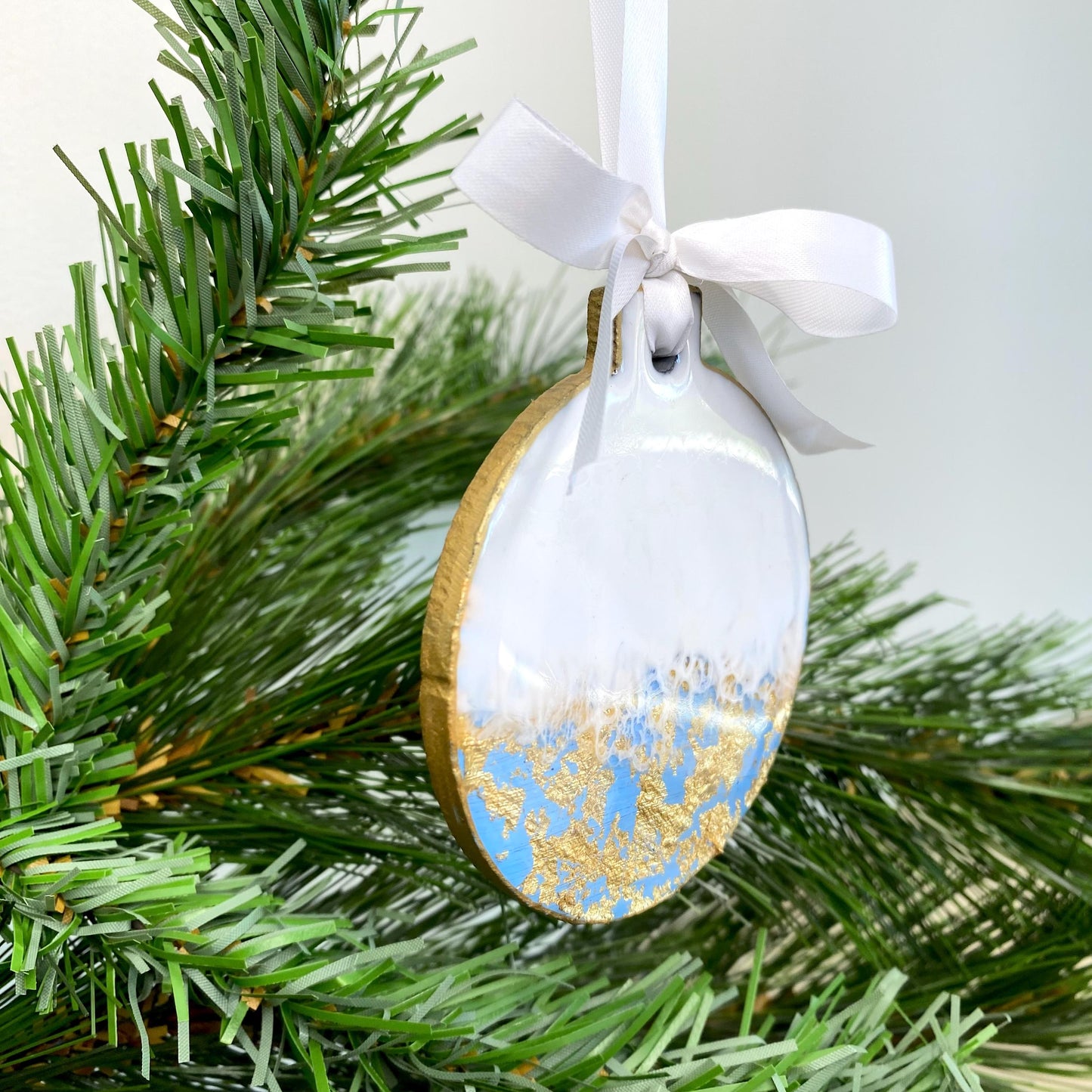 Close-up of blue slate resin Christmas ornament, showing non-personalised design, hand-painted gold edges, and white ribbon for hanging.