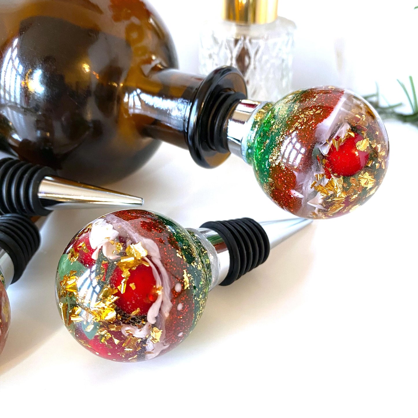 Close-up of Christmas resin wine stopper in wine bottle showing red berries, gold leaf, and glitter details