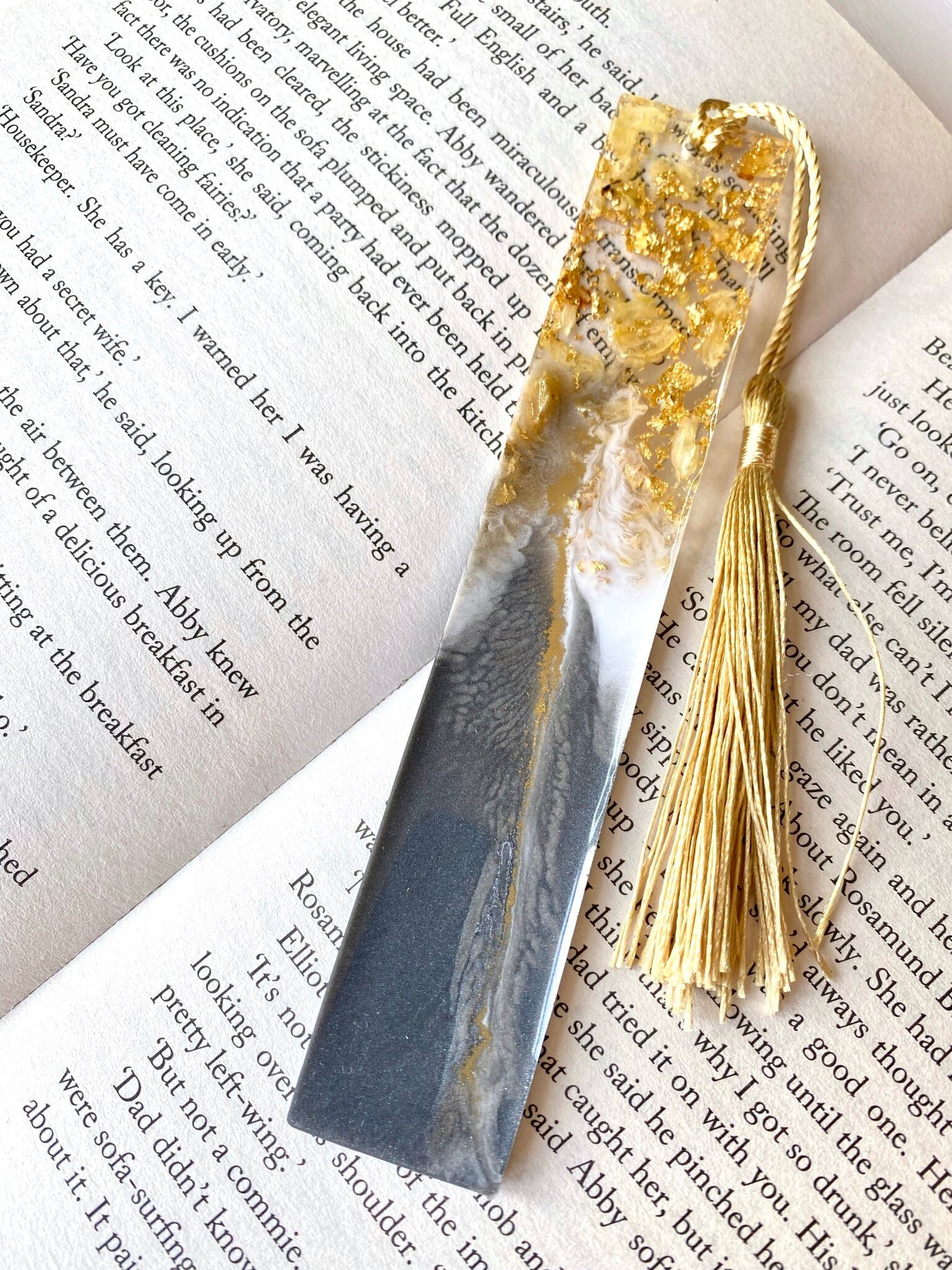 Grey and white resin bookmark with dried jasmine petals and gold leaf, non-personalised, featuring a gold tassel, elegant handmade bookmark for readers or gifts.