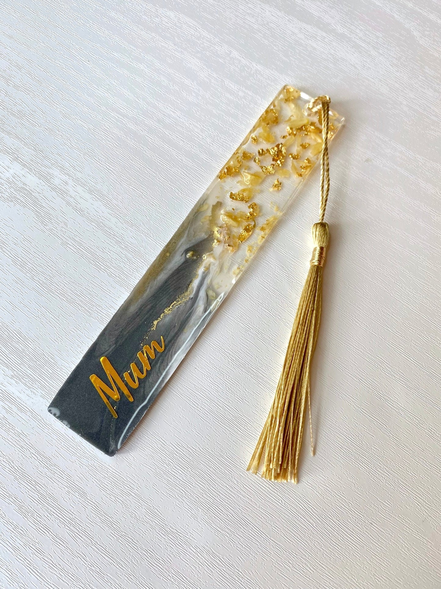 Full grey resin bookmark with dried jasmine petals and gold leaf, personalised with gold vinyl and featuring a gold tassel, elegant handmade bookmark for readers or gifts.
