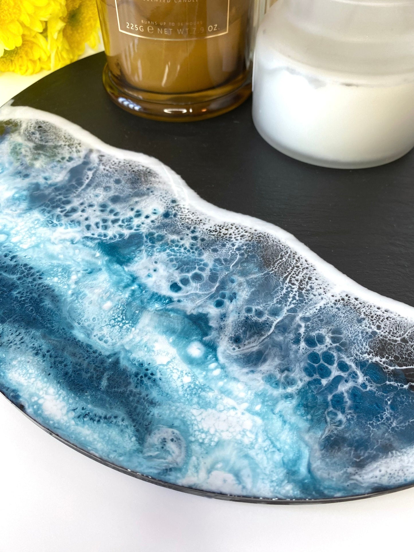 Close-up of handmade ocean resin charcuterie tray with slate base, styled with candles, highlighting blue and white resin wave details, coastal-inspired decorative serving board for home display