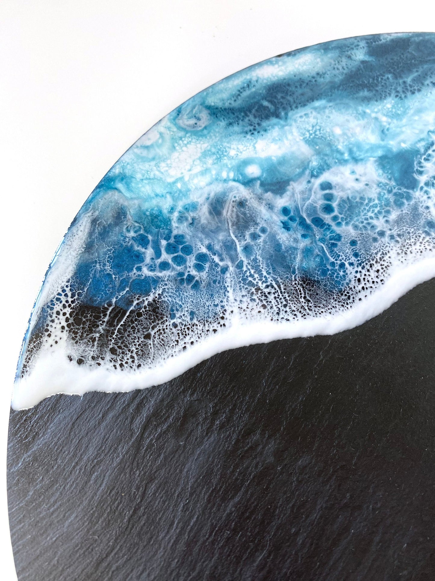 Close-up of handmade ocean resin charcuterie tray with slate base, highlighting blue and white resin wave details, showcasing coastal-inspired craftsmanship for serving or display