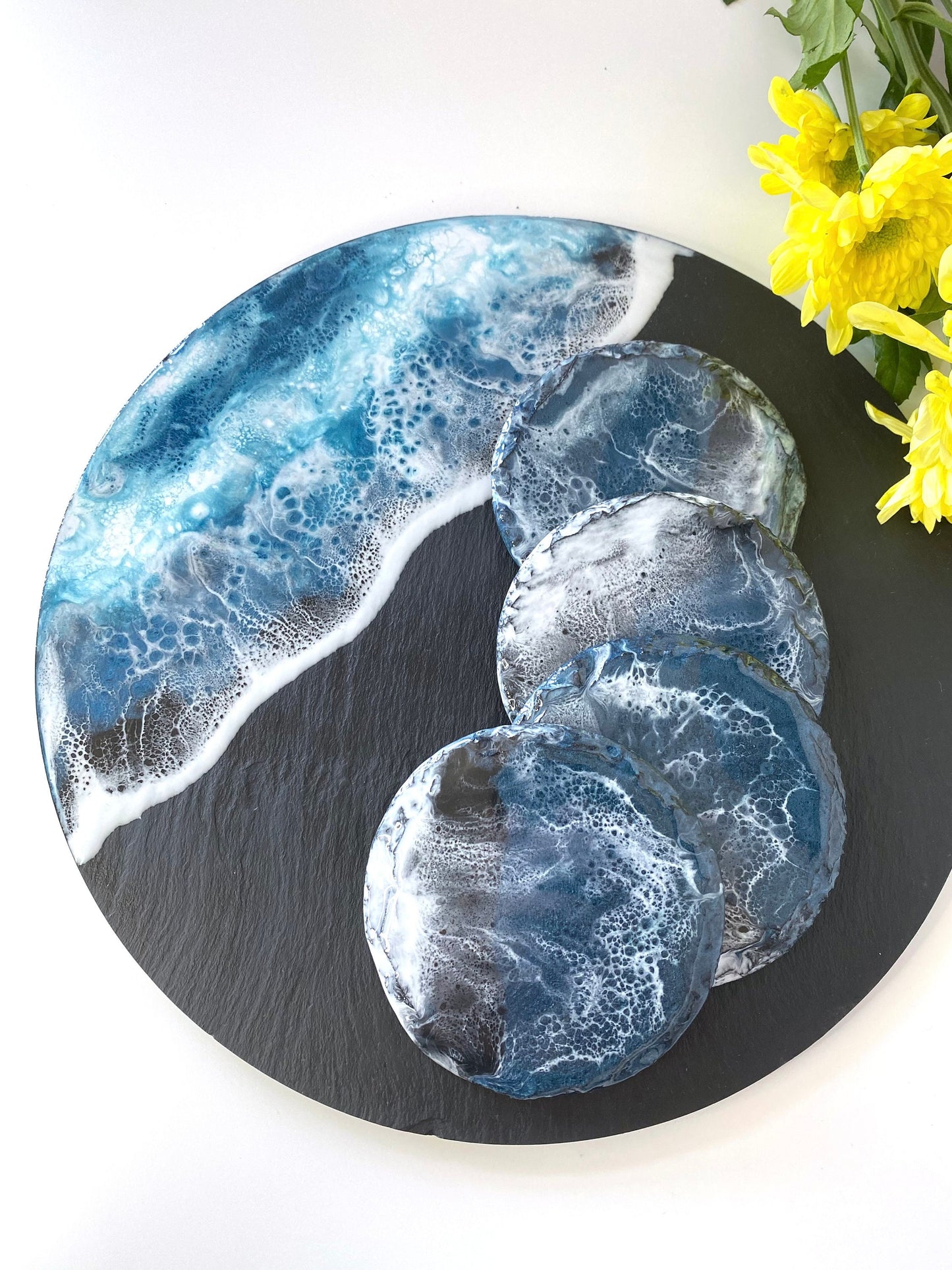 Handmade ocean resin charcuterie tray with slate base, styled with four matching resin coasters featuring the same blue and white wave design, coastal-inspired serving and decorative set for home entertaining, coasters sold separately.