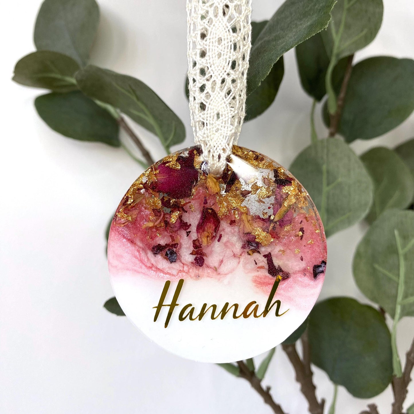 Personalised resin Christmas ornament with dried rose petals and gold leaf, hanging with a custom name in gold vinyl, pink and white colours, lace ribbon included