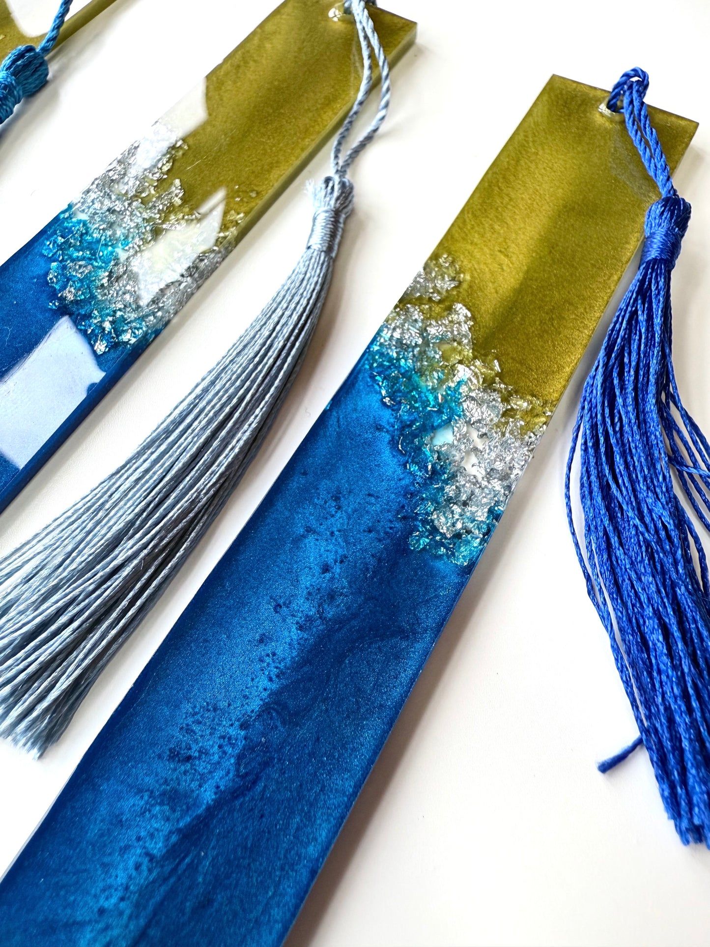 Close-up of handmade resin bookmark showing silver foil details. Blue, green, and silver celestial-inspired design with unique swirls, perfect gift for book lovers