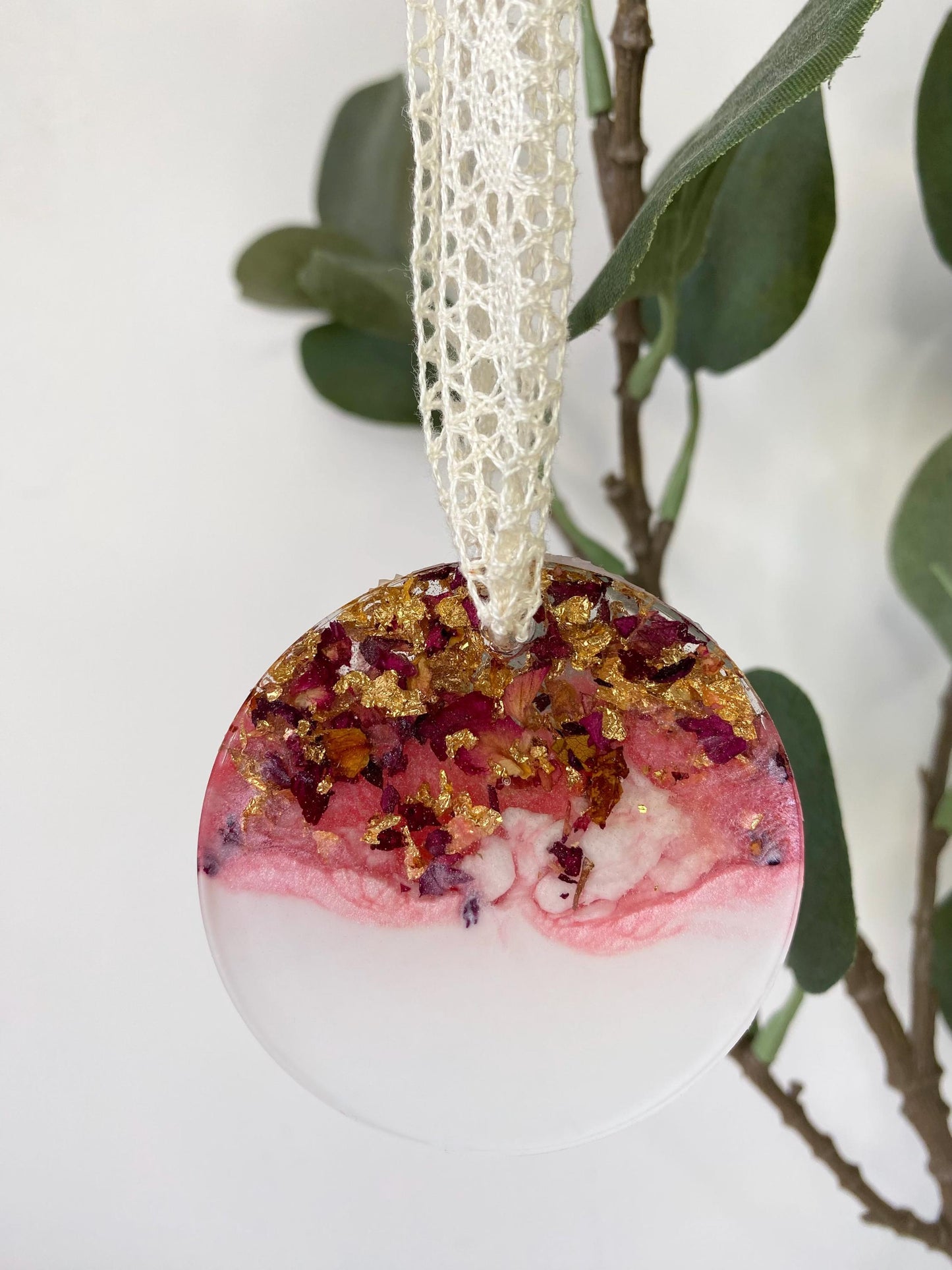 Non-personalised resin Christmas ornament with dried rose petals and gold leaf, pink and white colours, hanging on a tree with lace ribbon.
