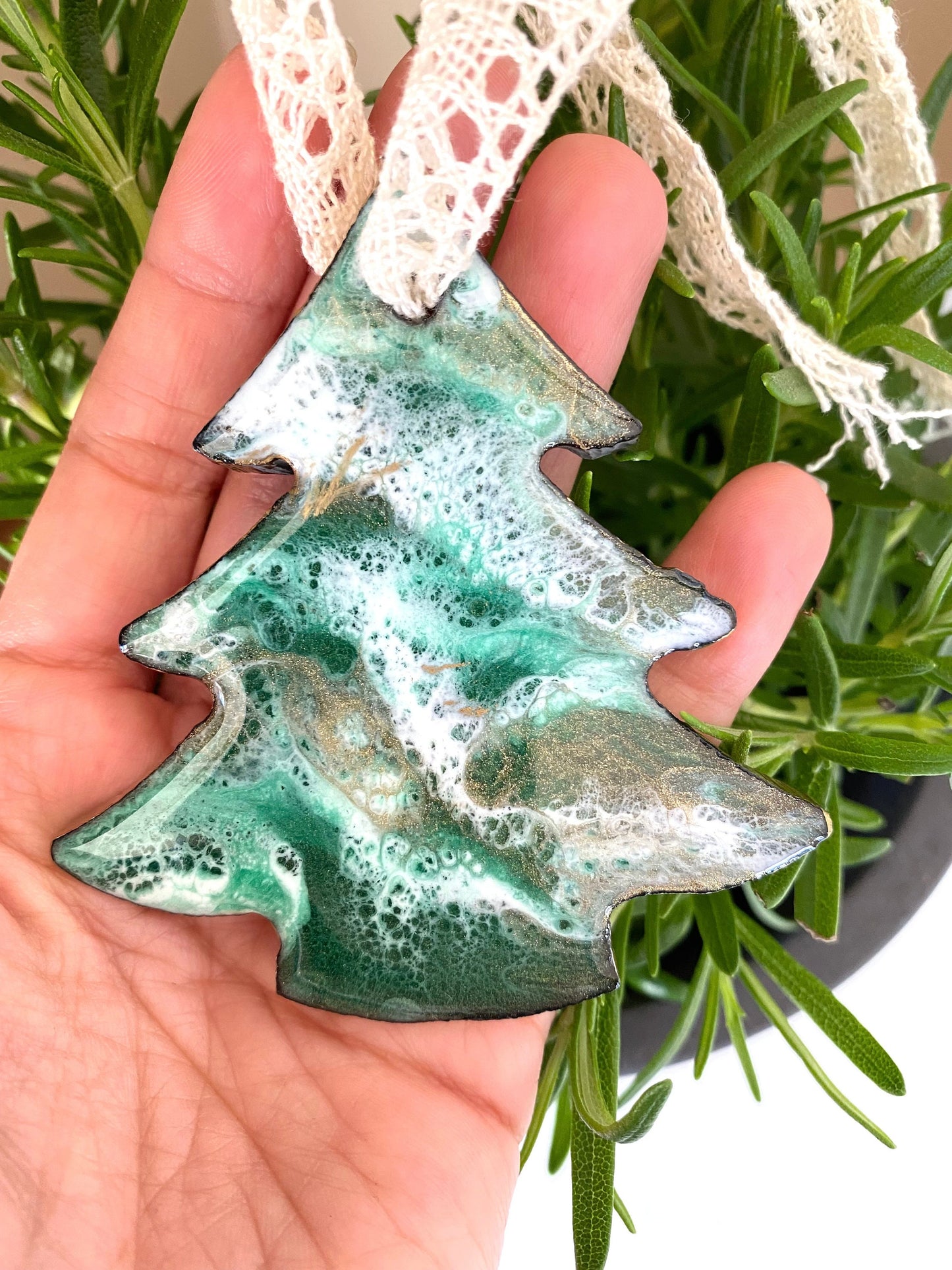Tree-shaped resin Christmas ornament on slate, green, white, and bronze/gold resin design with gold-painted edges and beige lace ribbon, personalised with 2025, held in hand to show size scale.