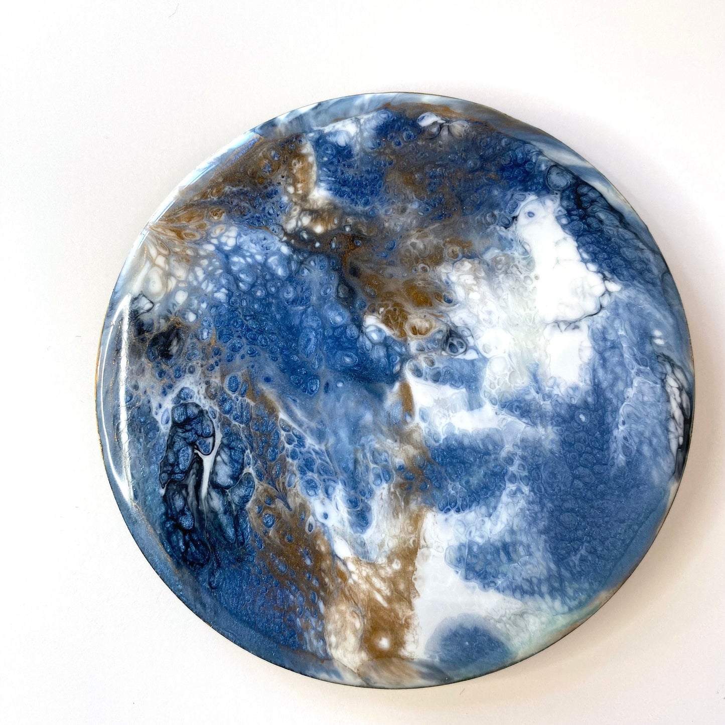 Handmade round slate resin coaster featuring unique blue, white, black, and gold epoxy pattern – no two coasters are identical.