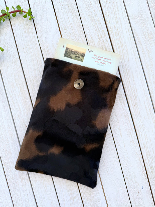 Black and brown animal print velvet book sleeve with a paperback book protruding from the top, showing how the sleeve holds a book.