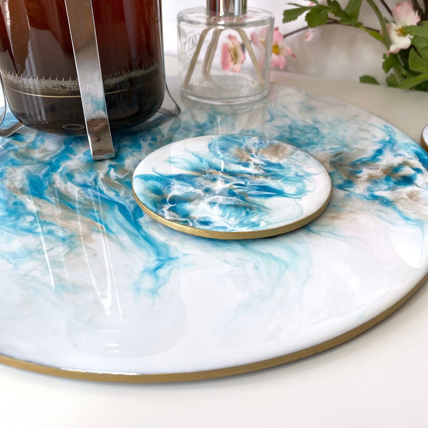 Close-up of matching resin coaster from white and blue resin tray set with slate base, showing coffee cup on coaster, highlighting hand-painted gold edges and elegant handmade design for home décor or serving