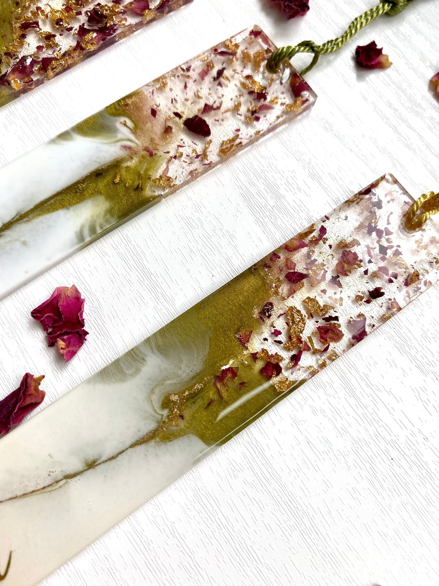 Close-up of the top section of white and green resin bookmarks showing clear resin with dried roses and gold leaf, highlighting intricate handmade details, personalised and non-personalised options.
