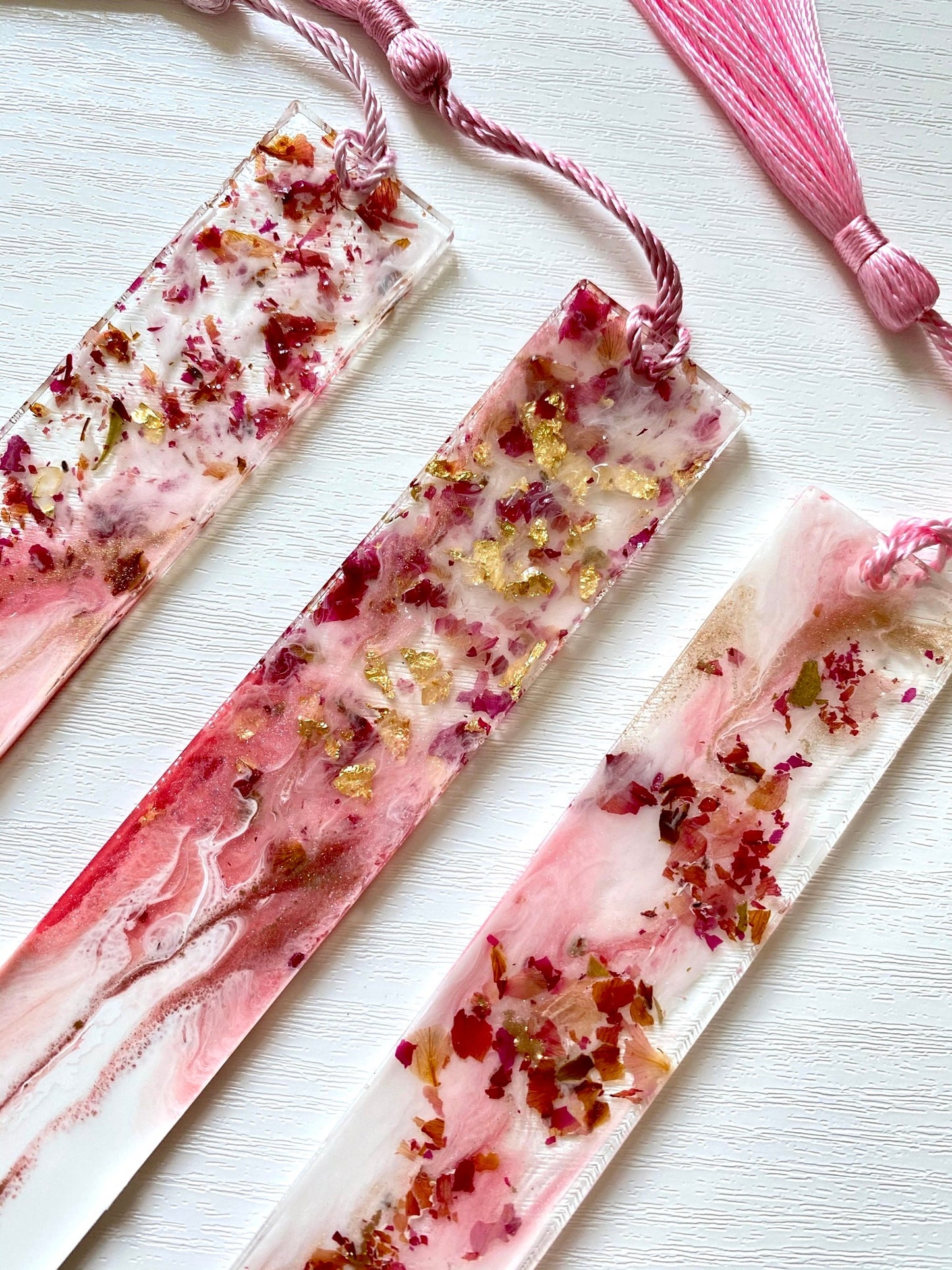 Super close-up of white and pink resin bookmark with dried roses and gold leaf, highlighting intricate handmade details and craftsmanship, personalised and non-personalised options.
