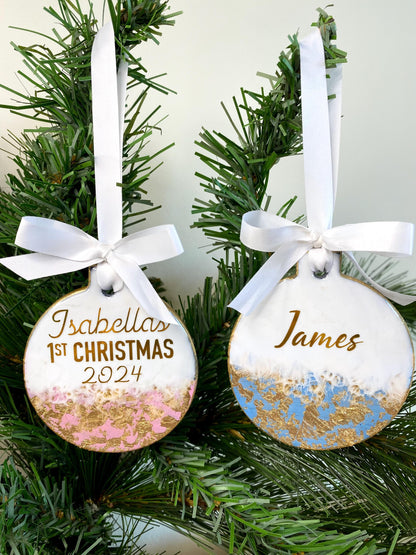 Blue and pink slate resin Baby’s First Christmas ornaments hanging on a decorated Christmas tree, personalised with name and First Christmas 2025 in gold, ready to display.
