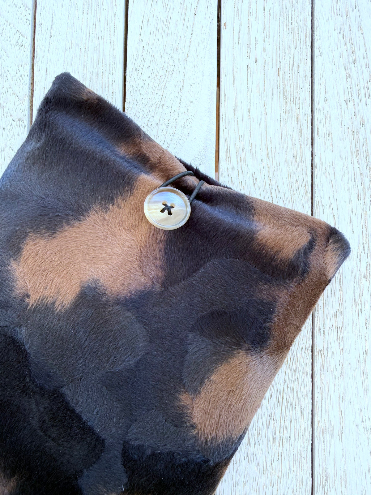Close-up of the upper section of an animal print velvet paperback book sleeve, showing its black and brown pattern and button fastening.
