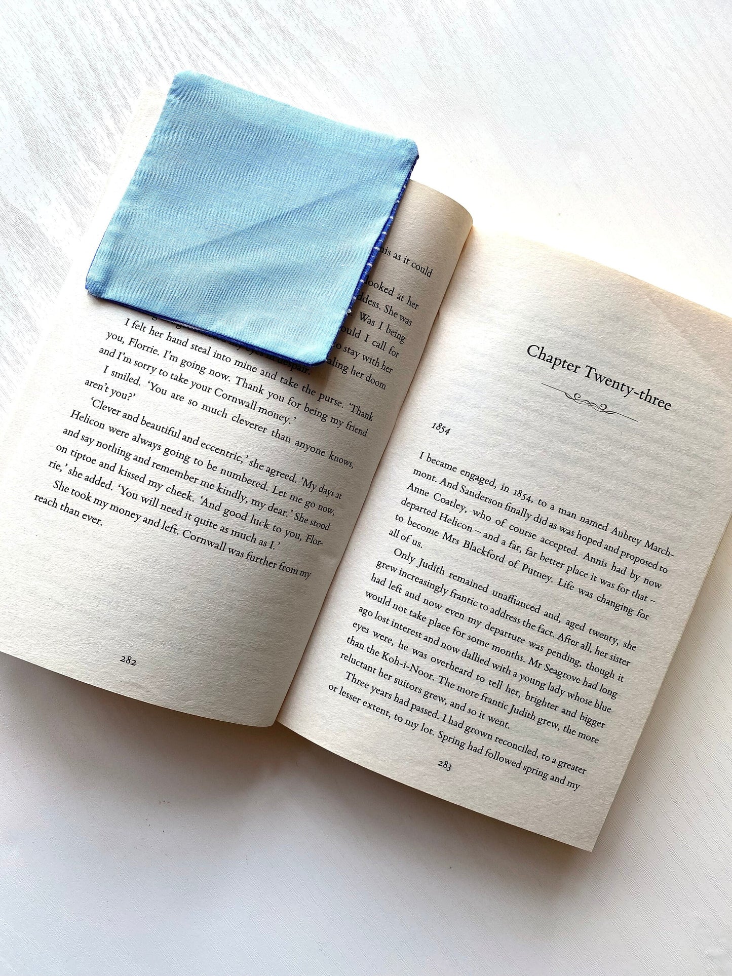 Open book with a blue fabric square on a white surface