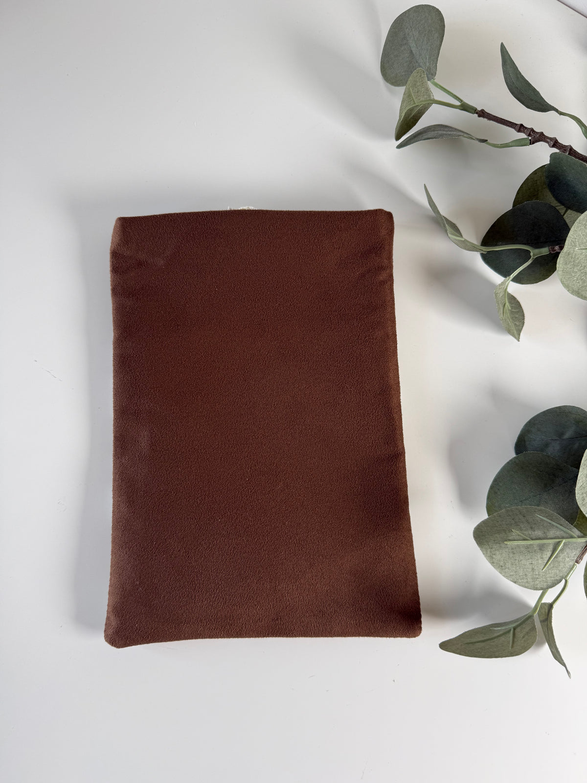 Back view of the handmade book sleeve showing its plain brown faux suede fabric without a floral pocket.