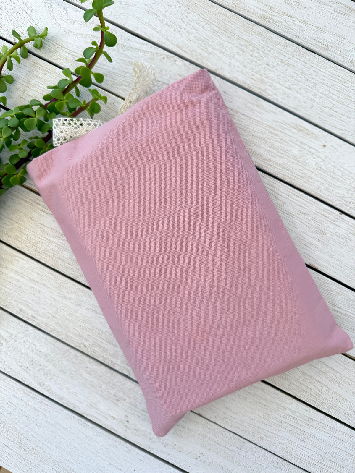 Back view of a handmade dusty pink fabric book sleeve, showing the plain pink fabric and fully covered reverse side.