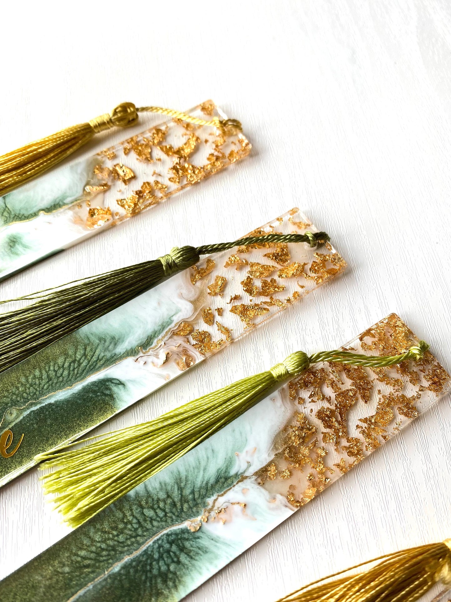 Close-up of the top of green resin bookmarks showing clear resin with gold leaf, highlighting handmade details and craftsmanship, personalised and non-personalised options.