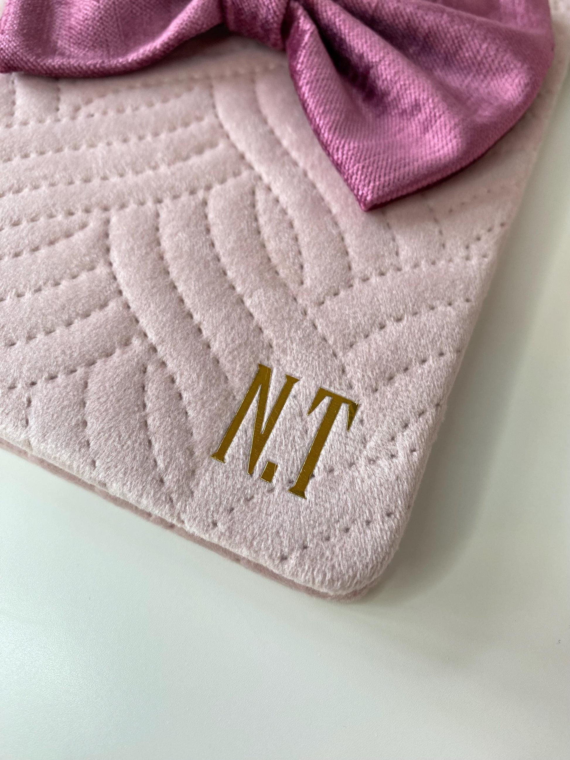 Close-up of pink A5 luxury velvet notebook with hand-sewn bow, showing gold initials personalisation on quilted cover