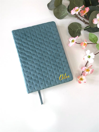 Teal A5 luxury velvet notebook with quilted cover, plain design, personalised with a name in gold, displayed on a white surface