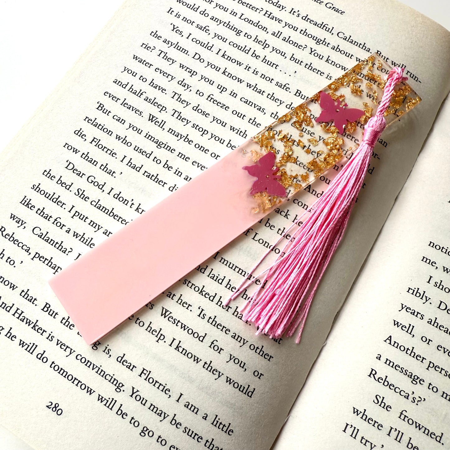 Non-personalised pink resin bookmark with butterfly design on an open book, featuring a matching tassel.