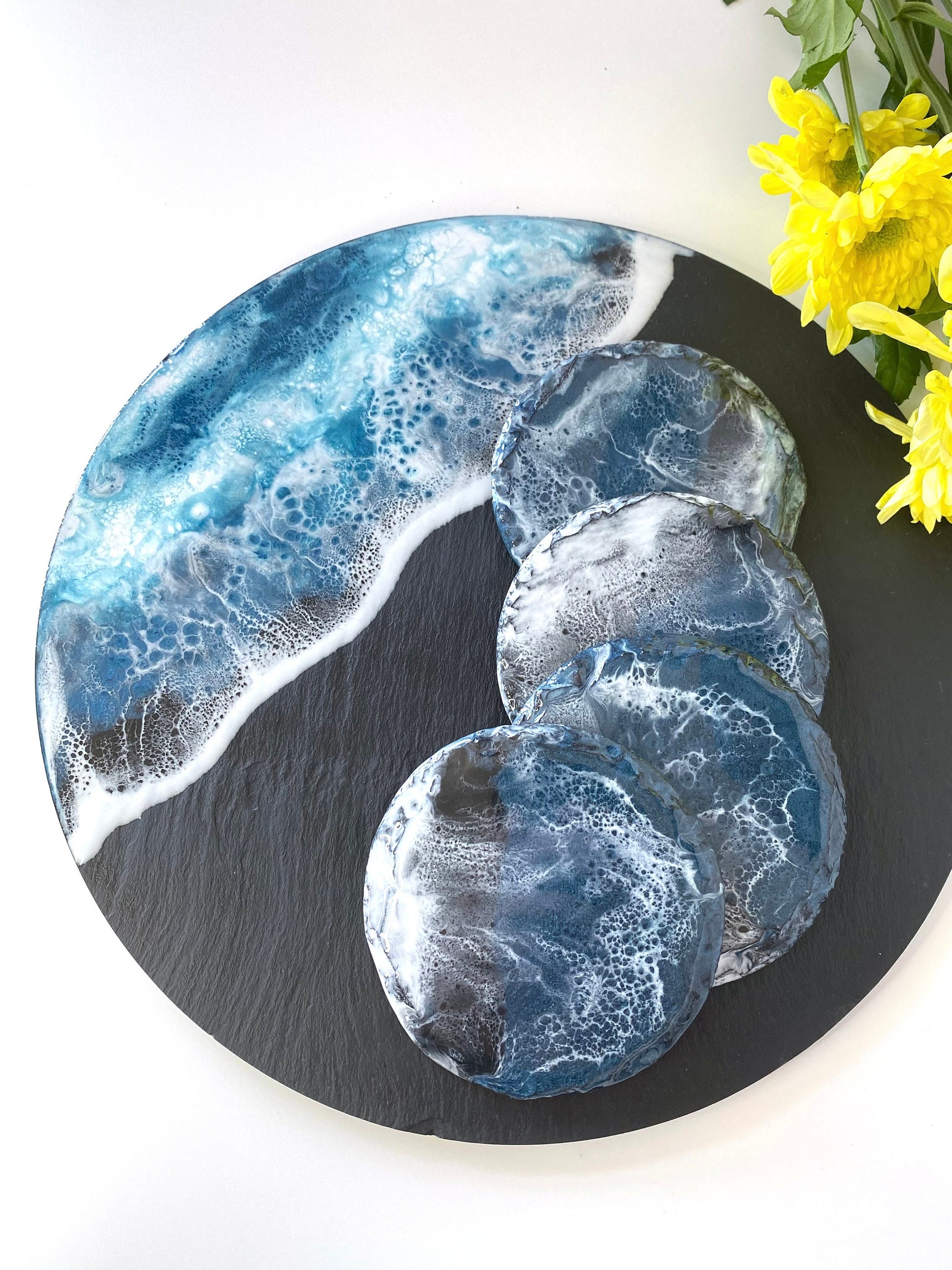 Handmade ocean resin charcuterie tray with slate base, styled with four matching resin coasters featuring the same blue and white wave design, coastal-inspired serving and decorative set for home entertaining, coasters sold separately.