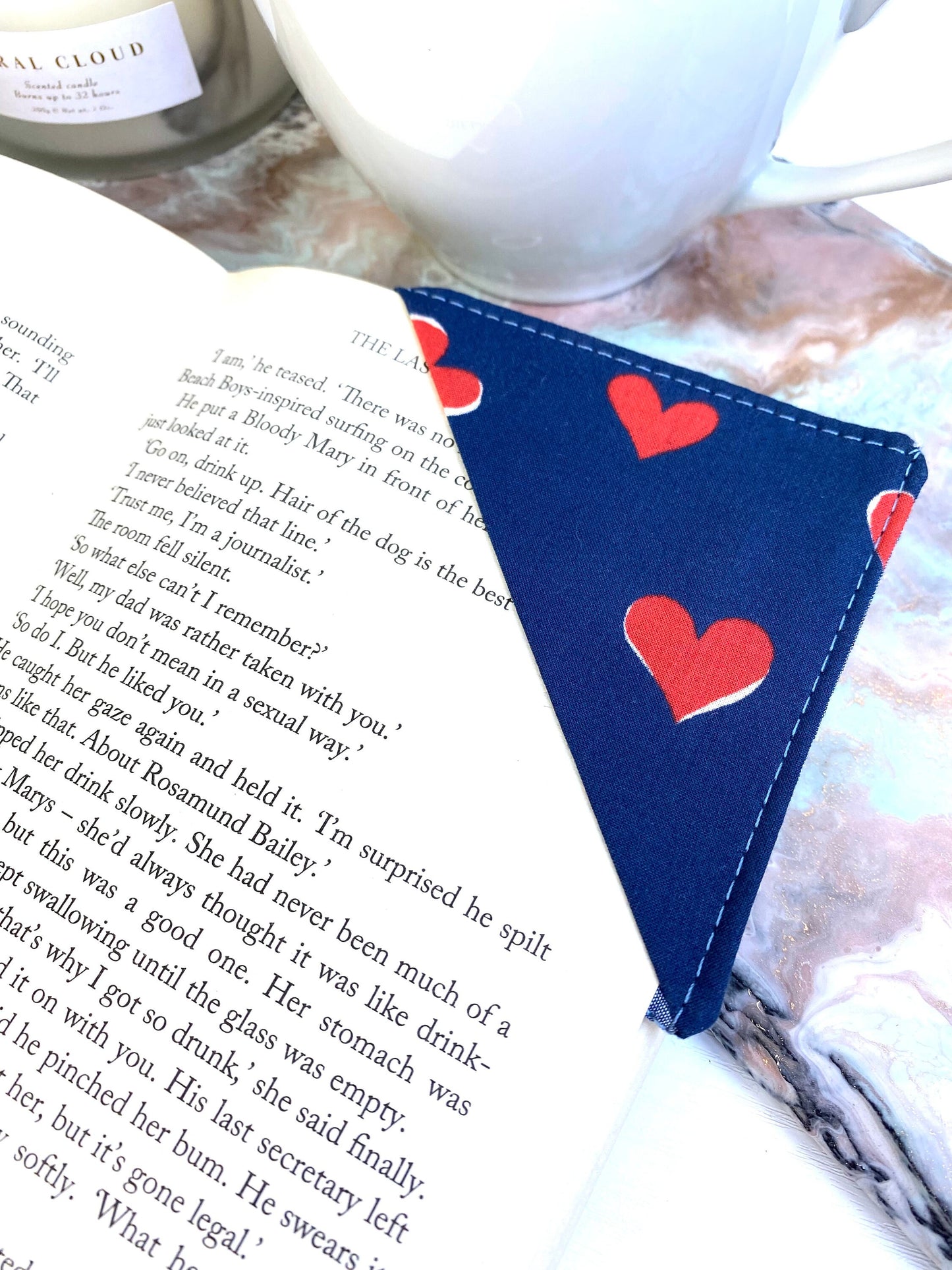 Personalised handmade fabric corner bookmark in Blue with Red Hearts design, placed on a book page – ideal gift for book lovers, teachers, and reading enthusiasts.