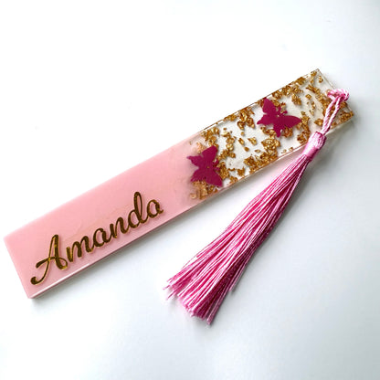 Personalised pink resin butterfly bookmark on a white surface, customised with gold vinyl and featuring a matching tassel.
