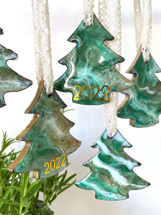 Personalised tree-shaped resin Christmas ornaments on slate, green, white, and bronze/gold resin design, gold-painted edges, beige lace ribbons, hanging to show all angles, personalised with 2025 or custom year.