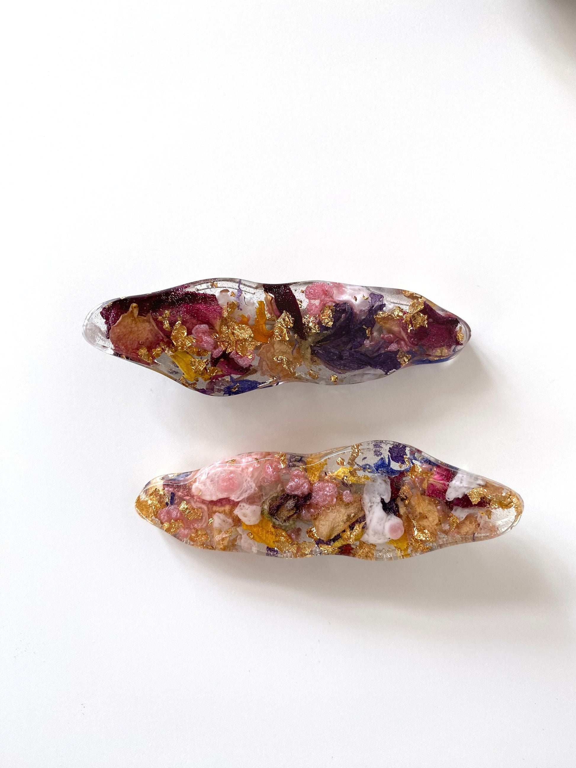 Two multicolored resin hair clips on a white background