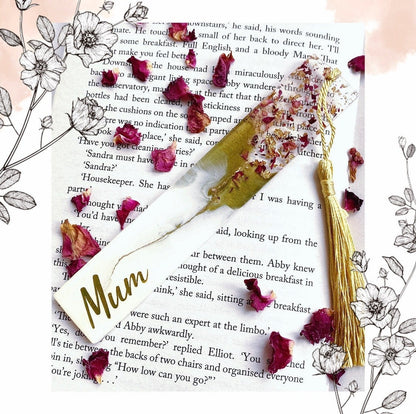 Close-up of white and green resin bookmark with dried roses and gold leaf, personalised with gold vinyl, inside an open book, showing handmade details, ideal gift bookmark for readers.